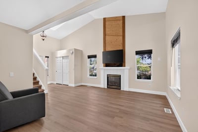 Spacious living area features high ceilings, a cozy fireplace, and abundant natural light throughout.