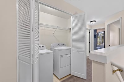 Bright and efficient laundry area featuring convenient side-by-side washer and dryer with ample storage space.