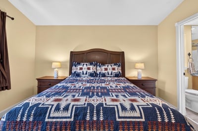 Cozy bedroom featuring a distinctive patterned quilt, warm lighting, and a welcoming atmosphere.