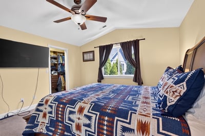 Cozy bedroom featuring a vibrant patterned bedspread, ample storage, and a window with natural light.