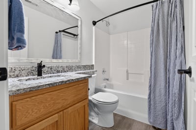 Modern bathroom featuring granite countertops, a spacious tub, and a sleek, organized design for functionality.