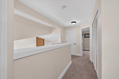 Bright and spacious hallway leading to multiple rooms, featuring soft carpet and modern design elements.