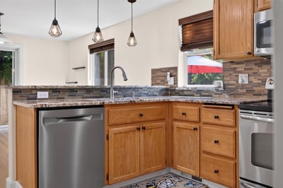 Modern kitchen featuring stainless steel appliances, wooden cabinetry, and unique tile accents, perfect for culinary enthusiasts.