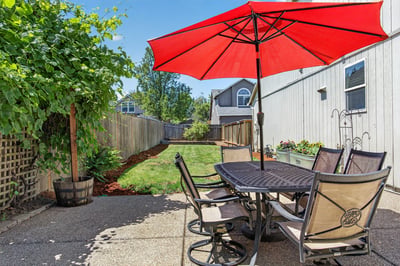 Spacious backyard oasis features a shaded dining area, perfect for entertaining or relaxing outdoors.