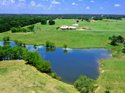 PROPERTY AERIAL...View Of Beautiful Land, Home, Lake, Pond And Outbuilding
