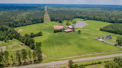 Expansive rural property featuring open fields, a pond, and versatile structures ideal for farming or recreation.