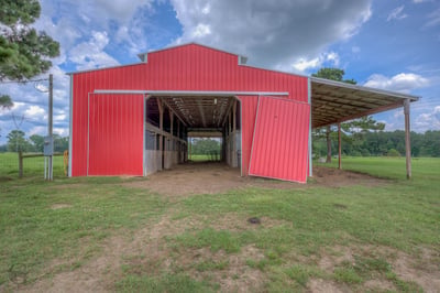 Spacious red barn with ample storage and covered space, perfect for livestock or equipment on expansive land.