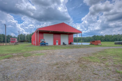 Spacious red barn with expansive grounds, ideal for storage or recreational use, near a tranquil pond.