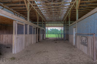 Horse barn with multiple stalls and ample room for riding, conveniently located near lush pastures.