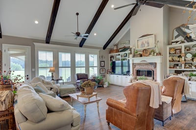 Bright living room featuring high ceilings, abundant natural light, and a cozy fireplace with scenic views.