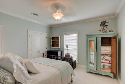 Bright bedroom featuring a vintage armoire, spacious layout, and abundant natural light in a tranquil setting.