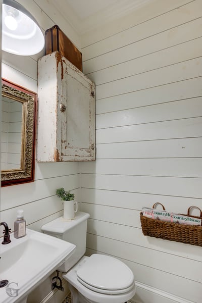 Cozy half bath featuring shiplap walls, vintage accents, and practical storage for a unique touch.