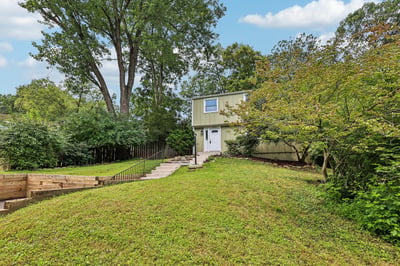 This two-story home features a spacious yard, mature trees, and a welcoming entrance.