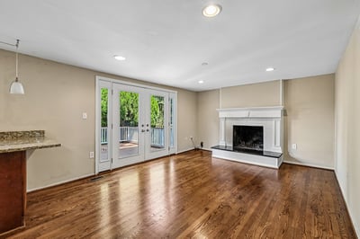 Bright, open living space featuring large windows, hardwood floors, and a cozy fireplace for gatherings.