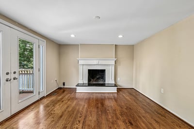 Bright and inviting living area features a cozy fireplace, large windows, and rich hardwood flooring.