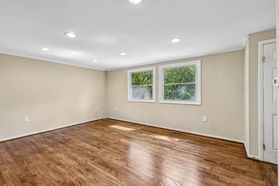 Spacious, well-lit room with hardwood floors and ample natural light from large windows.