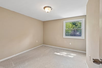 Spacious bedroom with natural light, featuring a window and versatile space for personalized design.