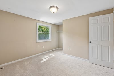 This versatile bedroom features neutral tones, natural light, and ample space for personal design.