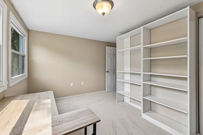 Bright and spacious room featuring built-in shelving and large windows, perfect for a home office or study.