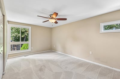 Bright and spacious room featuring new carpet, a ceiling fan, and a view of the outdoors.
