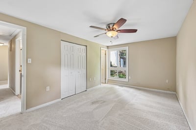 Spacious bedroom featuring a ceiling fan, natural light, and convenient access to a private balcony.