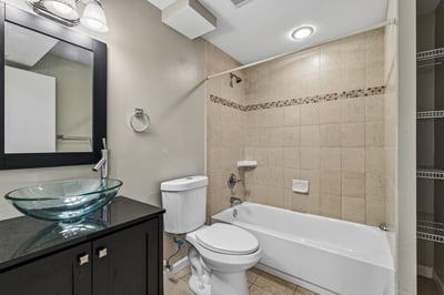 Modern bathroom featuring a sleek design, glass vessel sink, and convenient tub-shower combination.