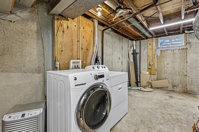 Spacious basement laundry area featuring modern washer and ample storage potential for future projects.