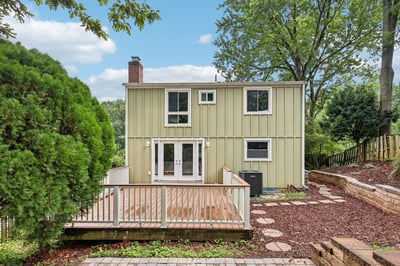 Discover this inviting home featuring a spacious deck, surrounded by lush greenery and easy outdoor access.