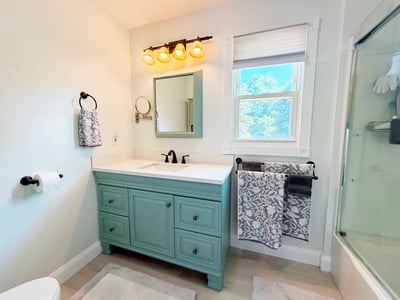 Full Bath w/ New LVP flooring 2026, newer vanity/sink & cabinets refreshed in 2026, cordless shade, OH vent/light, fiberglass tub/shower w/ updated glass sliding doors