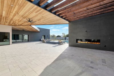 Covered outdoor living space with wood-paneled ceiling, sleek fireplace, and views of the pool area. This Paradise Valley home is designed for luxury outdoor entertaining and relaxation.