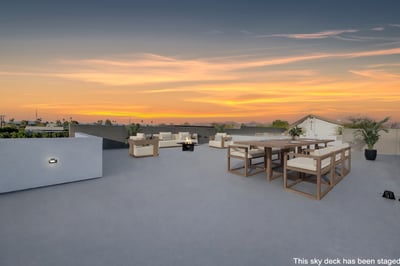 Virtually staged sky deck showcasing outdoor dining and lounge areas with panoramic views. This Paradise Valley home offers a unique rooftop space ideal for entertaining.