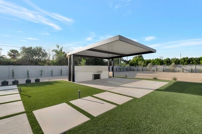 Backyard featuring covered trellis, built-in outdoor kitchen, and green turf areas. This Paradise Valley home is perfect for hosting and outdoor gatherings.