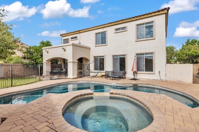 Relax in your private Goodyear backyard oasis featuring a heated pool, spa, paver patio, and covered outdoor space designed for year-round enjoyment.