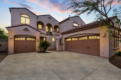 Beautifully lit exterior showcasing this Goodyear home s inviting facade, spacious driveway, and 3-car garage under a vibrant twilight sky.