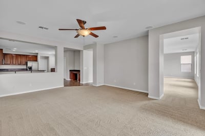 Wide-open living area with soft carpet and direct sightlines into the kitchen, highlighting the home's functional layout and updated finishes.