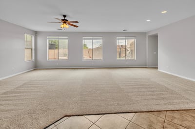 Large family room featuring multiple windows, neutral tones, and comfortable carpet, ideal for relaxing or entertaining guests.