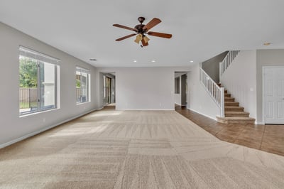 Spacious living room with open staircase design and abundant natural light, enhancing the home's open and airy feel.