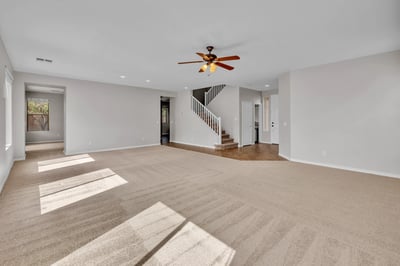 Sunlit living space with expansive carpeted area and open layout, perfect for modern living in this Goodyear property.