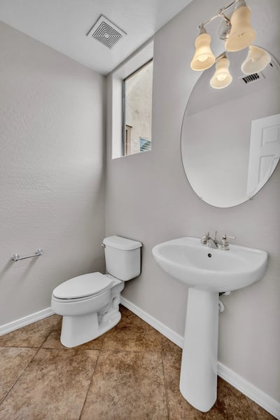 Clean and functional half bath with pedestal sink and neutral finishes, conveniently located for guests.