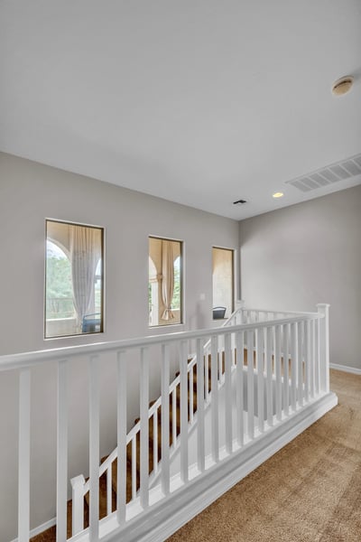 Open upstairs hallway with natural light and railing detail, connecting bedrooms while enhancing the home's spacious feel.
