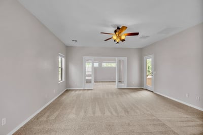 Spacious primary bedroom with ceiling fan and access to a private sitting area, offering added flexibility and comfort.