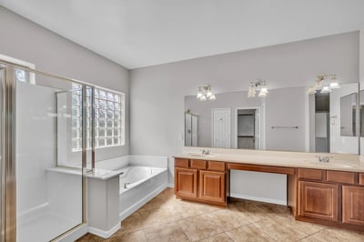 Elegant primary bathroom with soaking tub, dual sinks, and separate shower, complemented by natural light and spacious design.