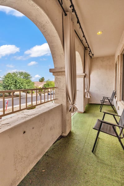 Covered balcony with elegant arches, outdoor curtains, and seating, offering a peaceful outdoor living space to enjoy the Goodyear lifestyle.