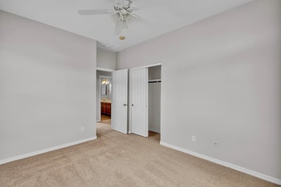 Convenient bedroom located near a bathroom, featuring neutral tones, plush carpet, and ceiling fan for comfortable living in Goodyear.