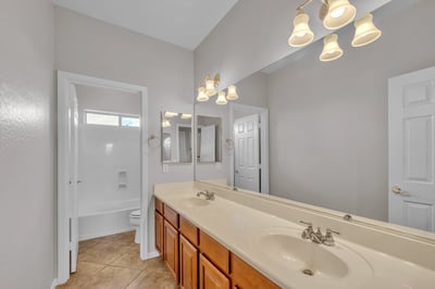 Well-appointed bathroom with dual sinks, large mirror, and wood cabinetry, offering ample storage and functionality in Goodyear.