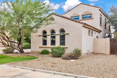 Side exterior featuring desert landscaping, mature greenery, and low-maintenance design for easy living in Goodyear.