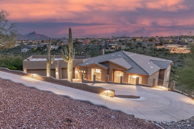 Captivating sunset photography highlights the home's elevated hillside location, desert surroundings, and warm architectural lighting. This private retreat offers incredible evening views and lock-and-leave convenience.