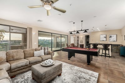 Spacious game and entertainment room featuring a pool table, built-in wet bar, and large sliding glass doors opening to the covered patio. This versatile lower-level retreat combines indoor comfort with stunning Fountain Hills scenery.