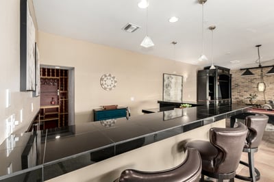 Elegant entertainment bar featuring expansive counter seating, pendant lighting, and built-in wine storage. This thoughtfully designed gathering space complements the home's open-concept layout and enhances everyday entertaining.