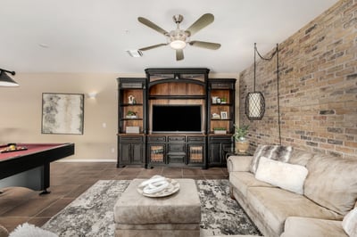 Inviting recreation space with custom built-in media cabinetry, stylish brick accent wall, and comfortable seating area. Perfect for movie nights, game-day gatherings, or creating a dedicated entertainment hub within the home.